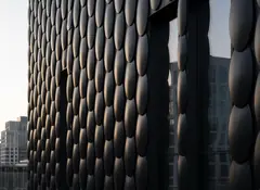 Building corner clad in dark oval metal scales